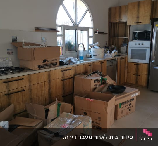 ארגזים פתוחים במטבח עם כלים ואריזות